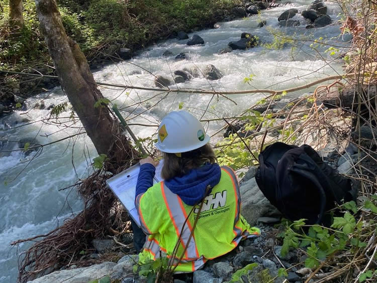 Biology team member conducting a steam survey using Ordinary High Water Mark methodology